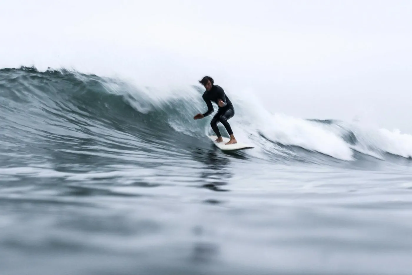 Un surfeur debout sur sa planche, bien fléchi, au creux d'une vague
